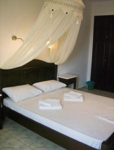 a bed with white sheets and white curtains on it at Evgatis Hotel in Kondiás
