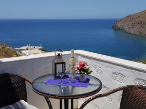 Sea View Apartments by Susi & Sofia في سكالا: طاولة مع كأس النبيذ والزهور على الشرفة