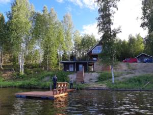 a man standing on a dock in front of a house on a lake at Hiekkaranta Holiday Home in Parikkala