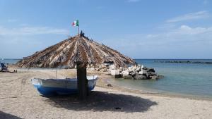 a boat on a beach with a straw hut at Villa sul mare in Francavilla al Mare