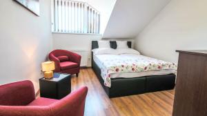 a bedroom with a bed and two chairs at White Apartman Siófok in Siófok