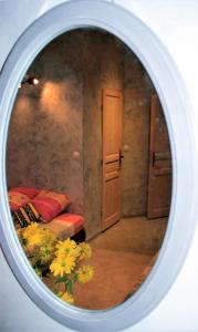 specchio che riflette una camera da letto con letto e fiori di Gite Derrière les Oliviers -Le Mas de la Cigale Bleue a Caumont-sur-Durance