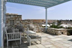 a patio with two chairs and a table and a stone wall at Ambelas Mare Apartments in Ambelas