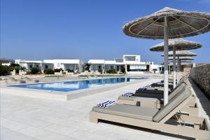 a swimming pool with lounge chairs and an umbrella at Ambelas Mare Apartments in Ambelas