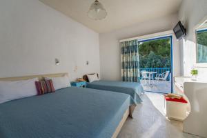 a bedroom with two beds and a large window at Vassilis Studios in Poros