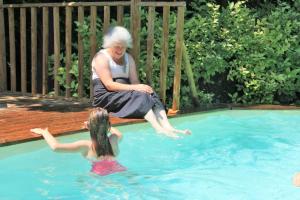 Una donna anziana seduta accanto a una ragazza in piscina di Gite Derrière les Oliviers -Le Mas de la Cigale Bleue a Caumont-sur-Durance