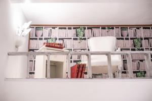 um quarto com uma cadeira branca e uma prateleira de livros em B&B Toma Street em Lecce