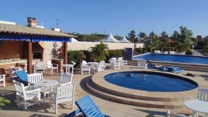 un patio con sillas blancas y una piscina en Apartamento Praia Taperapuan, en Porto Seguro