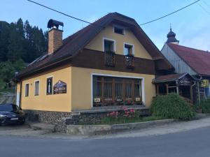 a small yellow house with a building at Chata Holica PIENINY in Lesnica