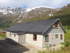 a building with a black roof with mountains in the background at Søndre Forøya Gård in Tromsø