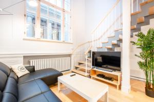 a living room with a couch and a tv and a staircase at Les Lofts St-Pierre - Par Les Lofts Vieux-Québec in Quebec City