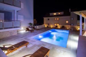a swimming pool with two loungers on a patio at night at Apartments Sara 4 in Bol