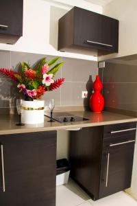 a kitchen with a counter with a red vase with flowers at Palm Garden Hotel Barbados in Bridgetown