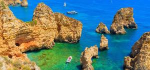 a group of rocks in the ocean with a boat at Ria Sunset House Alvor in Alvor