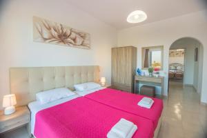 a bedroom with a large bed with a pink blanket at Villa Maroula in Afantou
