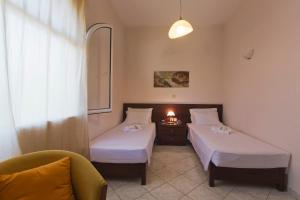 a room with two beds and a chair and a lamp at Achilles Country House in Corfu Town