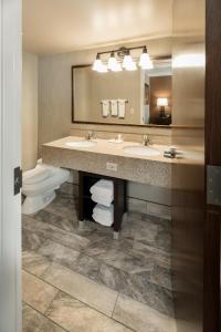 a bathroom with two sinks and a toilet and a mirror at Best Western Ramkota Hotel in Rapid City