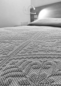 a black and white photo of a bed with a blanket at AppartArbus white suite in Arbus