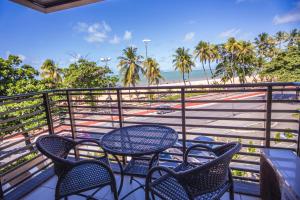 una mesa y sillas en un balcón con playa en Luxor Cabo Branco Home Service, en João Pessoa