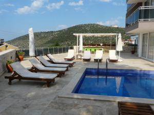 a pool with chaise lounge chairs and a swimming pool at Apollon Apartment in Kalkan