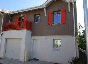 una casa con persianas rojas y garaje en Villa du Cabestan, en Andernos-les-Bains