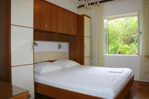 a bedroom with a bed with a wooden headboard and a window at Apartments Simuni 66 in Šimuni