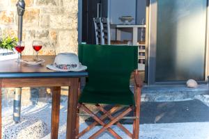 a table with a green chair and two glasses of wine at Natura Stone House in Sissi