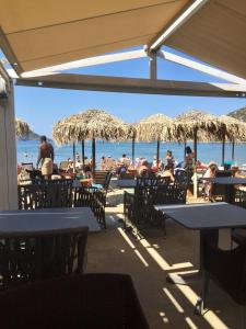 people sitting at tables on the beach under umbrellas at Sea Sight Boutique Hotel in Porto Rafti