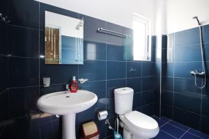 W wyłożonej niebieskimi kafelkami łazience znajduje się toaleta i umywalka. w obiekcie Vila Kleon w mieście Ksamil