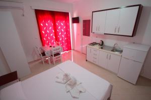 a white kitchen with red curtains and a sink at Hotel Four Islands in Ksamil
