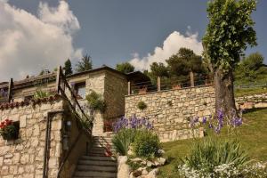 a stone house with a stone wall and a tree at Callort in Adrara San Rocco