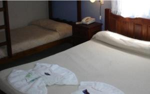 een slaapkamer met 2 bedden en een telefoon op een bed bij Hosteria Actinia in Villa Gesell