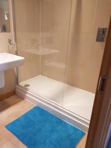 y baño con ducha y alfombra azul. en Vetrelax Basildon City Center Apartment en Basildon