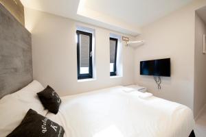 a bedroom with a white bed and two windows at K-Guesthouse Seomyeon 1 in Busan