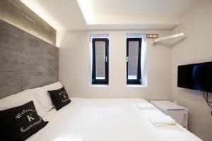 釜山にあるK ゲストハウス 西面 1のベッドルーム1室(白いベッド1台、窓3つ付)