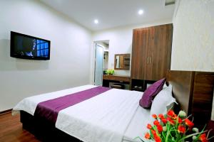 1 dormitorio con 1 cama y TV en la pared en Van Giang Hotel, en Ninh Binh