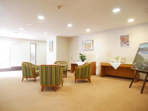 una sala de espera con sillas verdes y una mesa en Wisterian Life Club Usami, en Ito