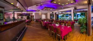 un restaurant avec des tables et des chaises roses et un bar dans l'établissement King Reef Resort, à Kurrimine Beach