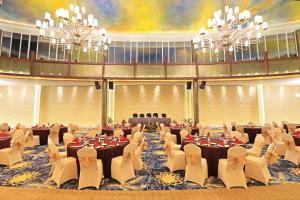 une grande salle de banquet avec des tables, des chaises et des lustres dans l'établissement Amartahills Hotel and Resort, à Batu