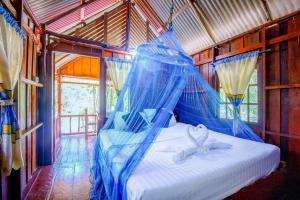 a bed in a room with a blue net at Khao Sok Palmview Resort in Khao Sok