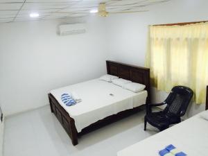 ein Schlafzimmer mit einem Bett und einem Stuhl darin in der Unterkunft Bindu Homestay in Wellawaya