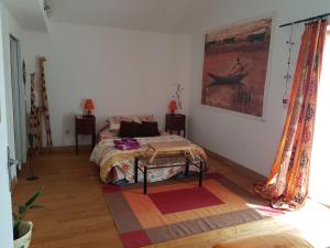 1 dormitorio con 1 cama y una pintura en la pared en Le ptit Venton maison écologique pour particulier ou professionnel, en La Jaille-Yvon