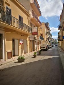 an empty city street with buildings and potted plants at Si Viaggiare Apartments in Partinico