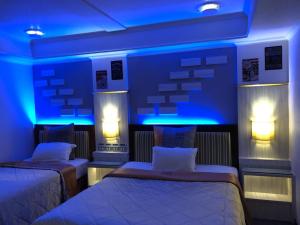 two beds in a room with blue lights at Beverly Commercial Motel in Luzhu