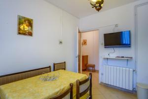 una sala da pranzo con tavolo e TV a schermo piatto di Apartments Beba a Mali Lošinj (Lussinpiccolo)