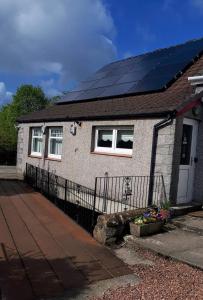 uma casa com painéis solares no telhado em The Old Smiddy Cottage and Apartment em Balloch