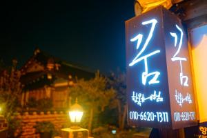 a sign on a pole with a lit up street at Hanok Dream in Jeonju