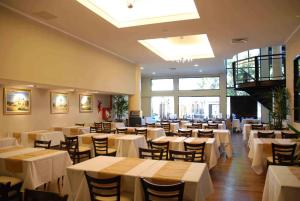 une salle à manger avec des tables et des chaises blanches dans l'établissement Condado Hotel Casino Goya, à Goya