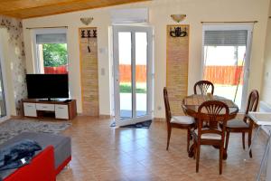 a living room with a table and chairs and a tv at Kenese Panoráma Apartman in Balatonkenese
