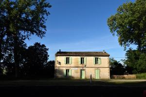 an old stone house with green doors and trees at gîte de la Domergue in Mas-Saintes-Puelles